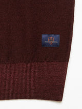 Close-up of the Marlon Knit - Prune by Blue de Gênes, a dark red Merino wool fabric with a ribbed hem and a navy rectangle patch displaying King of Cones in orange.