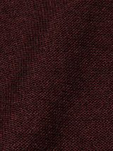 A close-up of Blue de Gênes Marlon Knit - Prune shows its dark red, textured fabric with a visible weave reminiscent of a reverse knit. The slightly coarse appearance reflects its subtle color variations.