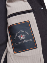 A close-up of the Amos Blazer - Dark Navy by Blue de Gênes reveals a cotton canvas lining with a sewn label featuring the brand crest—two lions and a shield—outlined in orange stitching.