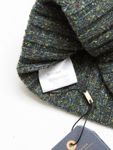 The Oscar Melange Beanie - Forest from Blue de Gênes is a 3-gauge knit made of 80% Wool and 20% Recycled Nylon. It features a textured dark green with multicolored speckles, highlighted by its labels.