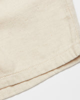 A close-up of the Abramo Desk Shorts - Natural by Blue de Gênes highlights the textured, woven surface of its beige cotton/linen blend fabric with a hemmed edge.