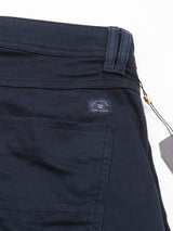 Close-up of Paulino Cargo Shorts - Navy by Blue de Gênes, showcasing a utility pocket, stitched seams, and a small fabric label with logo and text. A dark hang tag is also attached to the waistband using a beige string.
