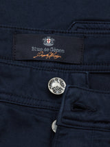 Close-up of Navy Paulino Cargo Shorts by Blue de Gênes, showcasing a branded label. A silver button with an embossed design is visible near the waistline. The durable thick military cotton fabric is stitched with matching thread.