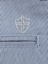Zoom in on the Elak Riga Shorts by Blue de Gênes, featuring a blue and white striped fine line cotton fabric with a stitched pocket and an embroidered shield-like emblem with a cross, complementing their relaxed regular fit.