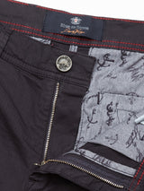 Close-up of Menzino Shorts - Dark Navy by Blue de Gênes featuring a partially open zipper. The waistband displays the brand label, while garment-dyed gray inner fabric sports an anchor and script pattern. Red stitching highlights the edges, and a silver button with engraved text enhances its refined look.