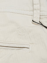 Close-up of Menzino Shorts - Stone by Blue de Gênes in garment-dyed fabric with an embossed shield logo featuring a cross, showcasing a belt loop and pocket with detailed stitching.