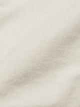 A close-up of the Menzino Shorts - Stone by Blue de Gênes reveals soft, smooth beige herringbone fabric with gentle shadows emphasizing the intricate weave design.