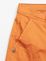 Close-up of Blue de Gênes Menzino Shorts - Apricot shows the cotton garment-dyed fabric, a side pocket with belt loop, and a small black button with a white cross near the pocket.