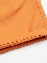 A close-up of the hem of Menzino Shorts - Apricot by Blue de Gênes, featuring visible stitching on vivid garment dyed fabric, contrasting against a plain white background.