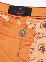 Close-up of Menzino Shorts - Apricot featuring a zipper, a metal button with an embossed logo, and visible interior lining with decorative patterns and text. Crafted from herringbone fabric, these shorts have a black label sewn into the waistband that reads Blue de Gênes.