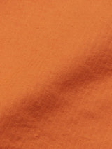 Close-up of the apricot Menzino Shorts by Blue de Gênes, featuring a subtle herringbone pattern that creates a soft wave across the surface, highlighting intricate weave details and vibrant color.