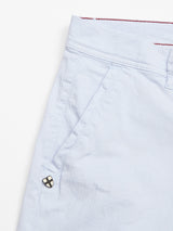 Close-up of Menzino Shorts - Blue Water by Blue de Gênes, crafted from herringbone fabric. They feature a side pocket with a small black square button in a four-square pattern and have an elegant red lining visible at the top hem.