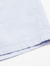 Close-up of Blue de Gênes Menzino Shorts in Blue Water: a light blue, garment-dyed fabric with visible edge stitching. The smooth, soft material has subtle wrinkles, reminiscent of fine herringbone.