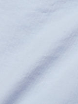 Close-up of the Blue de Gênes Menzino Shorts in Blue Water shows a light grey textured fabric with a subtle diagonal herringbone pattern and gentle shadows, hinting at a soft, smooth surface—ideal for chino shorts.