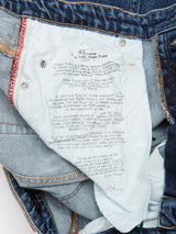 Close-up of the inside label of Repi Roll Jeans in mid blue denim by Blue de Gênes. The label features printed text on Renzo Pianos architectural works like Kansai Airport Terminal and the New York Times building, made with comfort stretch denim for everyday ease.