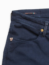 Close-up of Blue de Gênes dark navy Repi Grasso Jeans, showcasing a small pocket with a shield emblem. Above it, a label reads Made in Italy alongside an Italian flag icon. These regular slim-fit jeans feature visible stitching and a brass rivet by the classic five-pocket design.