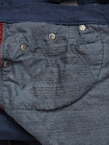 Close-up of Repi Grasso Jeans - Navy by Blue de Gênes shows care instructions on light blue denim typical of classic five-pocket jeans. Visible stitching and buttons highlight the design, with text faded and partially readable, reflecting Repi Jeans signature style.