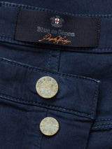 Close-up of navy Repi Grasso Jeans by Blue de Gênes, featuring a label and two engraved metal buttons. These buttons add a rustic touch to the classic five-pocket design, showcasing the timeless appeal of regular slim-fit craftsmanship.