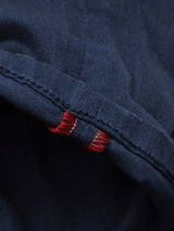 Close-up of navy fabric with intricate red stitching, similar to classic five-pocket jean designs. The contrast highlights Blue de Gênes attention to detail in their Repi Grasso Jeans collection.