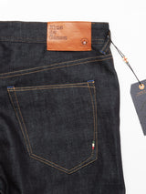 Close-up of Giacomo Selvedge Jeans in raw denim by Blue de Gênes, featuring a brown leather patch above the back pocket labeled with brand details and a touch of Italian craftsmanship, showcased by the Italian flag stitching on the pocket.