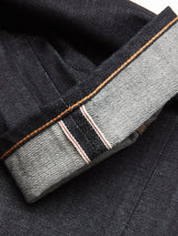 Close-up of Giacomo Selvedge Jeans - Raw Denim by Blue de Gênes in dark, rigid denim with cuff turned up to reveal the white selvedge edge accented by a red stripe, showcasing Italian craftsmanship and striking color contrast between the inner and outer sides.