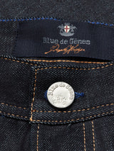 Close-up of Giacomo Selvedge Jeans - Raw Denim with a metallic button engraved with Blue de Gênes. Inside the waistband, a label features Italian craftsmanship with a crest logo and the brand name in blue and orange.