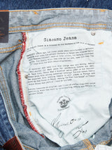 A close-up of Giacomo Maracas Jeans - Vintage Wash by Blue de Gênes turned inside out showcases Italian craftsmanship. A detailed inner waist label highlights the brands history and tribute to ancient Genoa workers, featuring visible stitching and English text.
