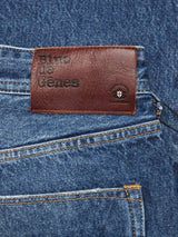 Close-up of a back pocket of relaxed fit Giacomo Maracas Jeans - Vintage Wash by Blue de Gênes, featuring a brown leather patch with a cross emblem, highlighting the Italian craftsmanship that distinguishes the denim.