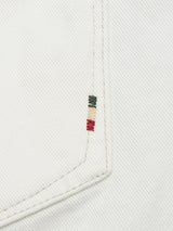 Close-up of Giacomo Bull WTH - White Denim by Blue de Gênes, highlighting its exquisite craftsmanship. Near the seam, three small horizontal embroidery lines in green, beige, and red sit vertically. Made in Italy with a subtle diagonal weave pattern.