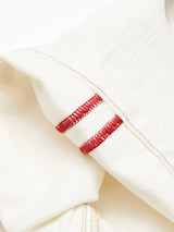 Close-up of Giacomo Bull WTH - White Denim by Blue de Gênes. The stone-washed, cream-colored fabric features two stitched red loops. Neat stitches contrast with the light material, showcasing a minimalist design typical of Italian-made Giacomo Jeans.