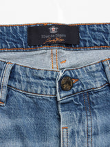 Close-up of Blue de Gênes Vinci Super Used Jeans, expertly crafted in Italy, highlights the waistband, button, and zipper. These regular fit jeans boast orange stitching and a detailed button, emphasizing craftsmanship.