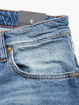 Close-up of Vinci Super Used Jeans by Blue de Gênes, highlighting a partially visible card peeking from the front pocket. Crafted in Italy, these denim jeans feature bronze rivets, contrast stitching, and a faded texture.
