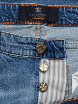 Close-up of Blue de Gênes Vinci Super Used Jeans in blue, featuring a partially unbuttoned fly that reveals a striped fabric lining. Expertly crafted in Italy, these jeans boast ornate metal buttons and prominent stitching, highlighting their quality.