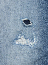 A close-up of Vinci Super Used Jeans by Blue de Gênes shows a small hole and frayed edges in distressed light blue comfort stretch denim. Expertly crafted in Italy, the weaving pattern contrasts beautifully with the worn area.