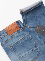 The expertly crafted Vinci Super Used Jeans by Blue de Gênes are made in Italy. These blue jeans feature a brown leather waistband patch, a small tag on the back pocket, a hanging brand tag, and are folded at the bottom for a classic regular fit style.