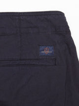 Close-up of the Mustang Cargo Pant - Navy by Blue de Gênes: Crafted from parachute cotton with utility pockets, it features a back pocket adorned with a shield-like logo patch. Dark stitching gives these dark-colored pants a sleek finish.