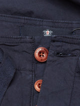 Close-up of Blue de Gênes Mustang Cargo Pant in Navy, showcasing utility pockets and three brown buttons. A fabric label near the waistband displays a small logo and text. The parachute cotton texture adds a slightly crinkled look.