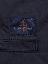 Close-up of a fabric patch on dark material, featuring a shield emblem with Blue de Gênes text in blue and orange stitching. Resembling the Mustang Cargo Pant - Navy, the patch is bordered by a stitched rectangular outline, suggesting utility pockets made from parachute cotton.