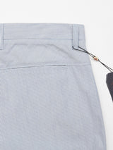 The Palto Riga Chino by Blue de Gênes showcases a close-up of blue and white pinstriped pants with a button fly, visible waistband, and a black tag attached. Crafted from lightweight cotton fabric, it offers a relaxed feel and beautifully highlights the upper section.