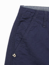 A close-up of the Lori Tarlo Chino - Navy by Blue de Gênes, featuring a relaxed fit and visible stitching. It highlights the navy cotton waistband with belt loops, a button, and a small triangular metal accent near the pocket. The fabric has a slightly textured appearance.