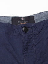A close-up of the Lori Tarlo Chino in navy shows a button closure and inner waistband detail with a label reading Lori Tarlo for Blue de Gênes. The textured, woven fabric suggests a relaxed fit design.