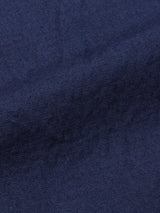 A close-up of the navy Lori Tarlo Chino by Blue de Gênes reveals a finely woven cotton fabric with a subtle diagonal pattern. The lighting accentuates its smooth surface and depth, evoking softness and the rich color characteristic of Lori Tarlos relaxed fit designs.