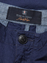 Close-up of the Lori Tarlo Chino in navy, featuring a button fastening. The waistband has a black label with Blue de Gênes and orange text underneath. The lighter blue denim on the waistband’s edge adds style and ensures a comfortable, relaxed fit.