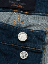 Close-up of the Vinci Topaz Jeans in rinse wash, featuring contrast stitching and two metal buttons. These Italy-crafted jeans showcase a top tag displaying the Blue de Gênes brand name.