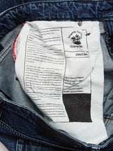 Close-up of the inside of expertly crafted Vinci Denova Jeans - Dark Blue Denim by Blue de Gênes, showing multiple white labels with brand, design, and care instructions set against dark blue denim fabric.