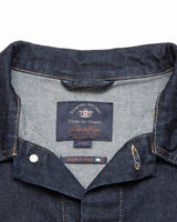 Close-up of the dark blue collar on the Cosimo Trucker Jacket by Blue de Gênes reveals visible stitching and an inner label reading Made in Italy. This western denim jacket features a classic texture and prominent button snaps.