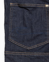 Close-up of the Cosimo Trucker Jacket by Blue de Gênes in dark blue denim, showcasing a back pocket with orange stitching and a subtle, darker blue design that evokes classic western style. The denim texture is clearly visible.