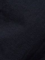 Close-up of a dark navy textured fabric, reminiscent of a Gabbiano Dobby Blazer by Blue de Gênes, with a fine knit pattern. The lighting enhances variations in the surface, highlighting the cotton comfort stretch that adds depth and softness.