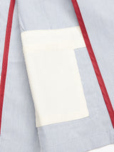 The Gabbiano Riga Blazer by Blue de Gênes, featuring a relaxed fit charm, displays vertical blue and white cotton yarn dye stripes inside. The pocket contrasts in plain white, enhanced with red stitching along the seams.