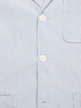 A close-up of the Gabbiano Riga Blazer by Blue de Gênes reveals blue and white vertical stripes in cotton yarn dye, featuring a pocket on the upper right. The relaxed fit includes two visible white buttons on the front placket.